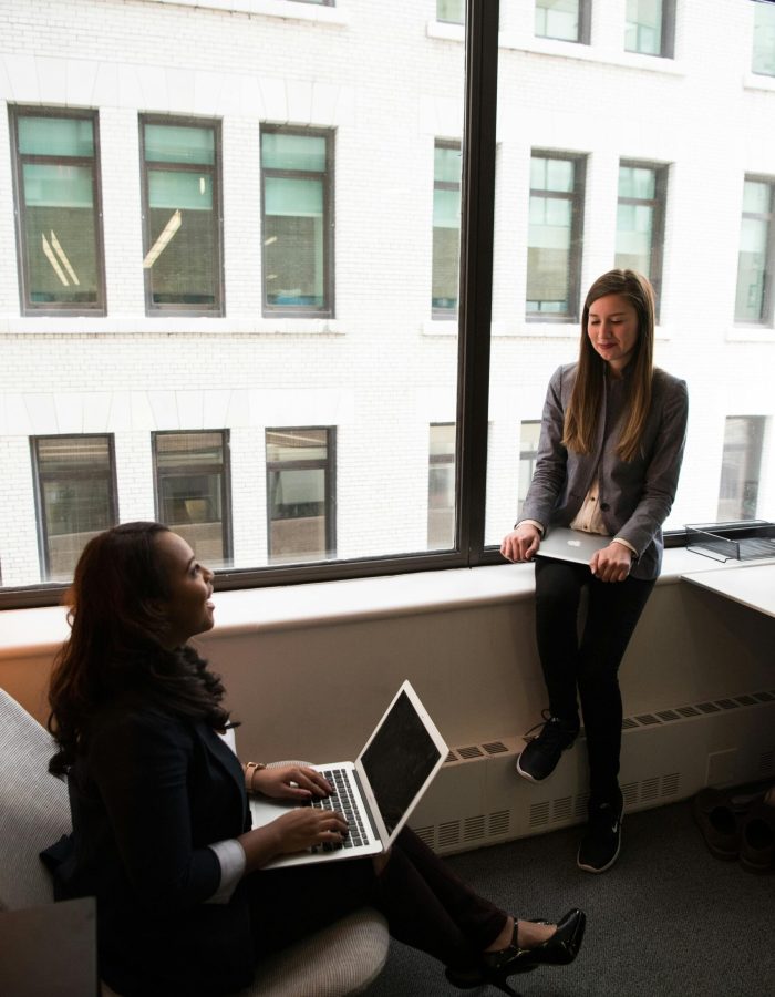 Two girls with laptops, showcasing the convenience of a $500 cash advance with no credit check.